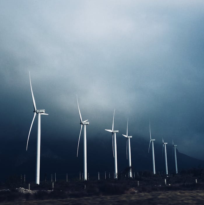 A line of wind turbines under a moody sky representing renewable energy and sustainability.